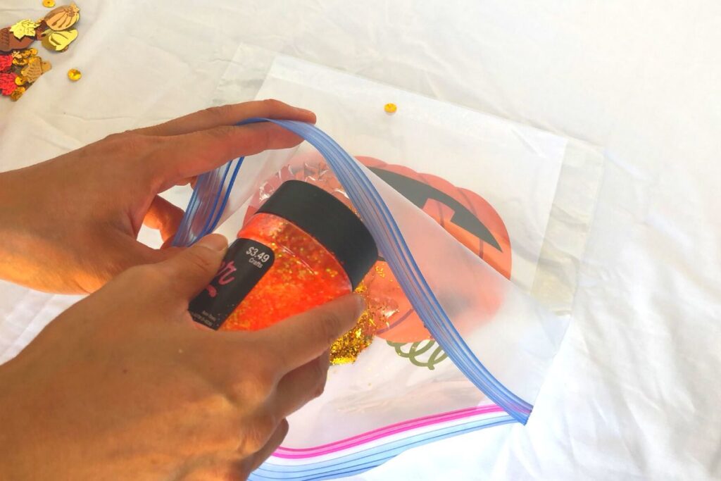 adding orange glitter to a fall sensory play bag
