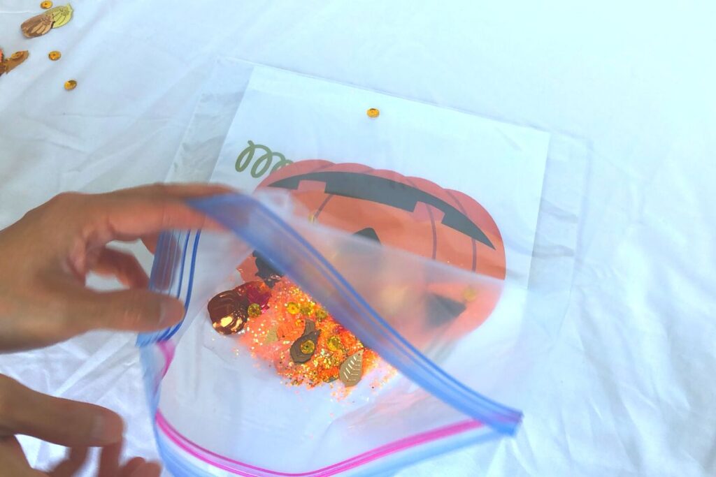 adding a shimmery fall color leaf sequin to our sensory bag activity